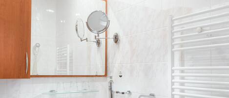 A modern bathroom with a white sink, wooden vanity, a large mirror, and a towel rack.