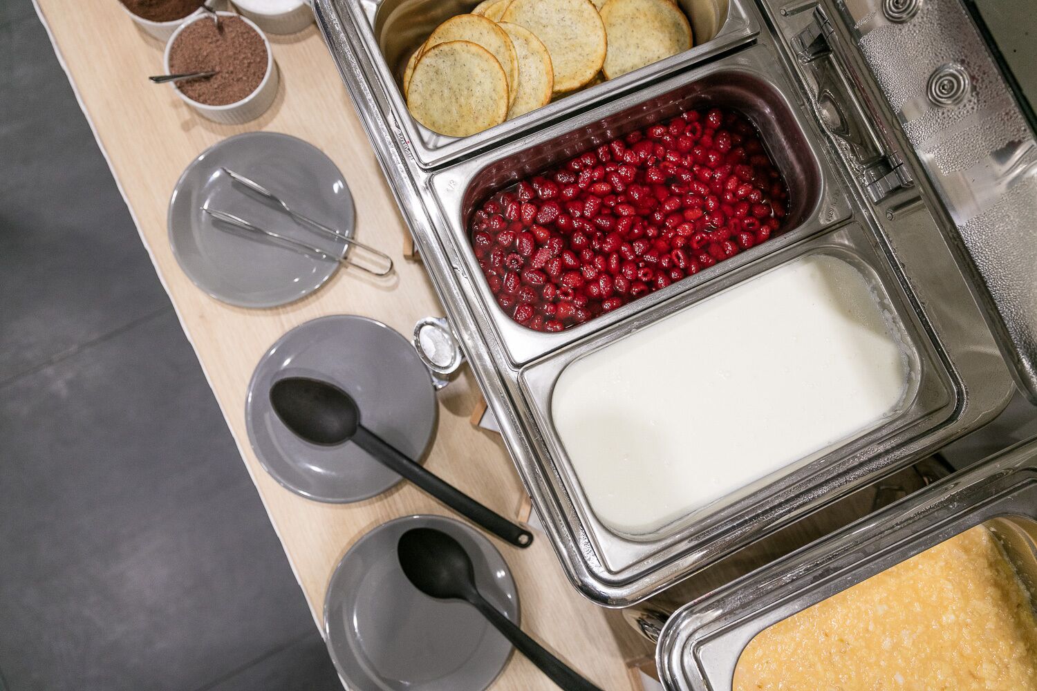 A buffet setup with various food items including biscuits, cranberry sauce, and a creamy dish, along with serving utensils.