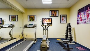 A gym with treadmills, an elliptical, and a weight bench. - City Hotel (Brno)