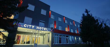 A modern hotel with a flat roof, large windows, and a sign reading "CITY HOTEL".