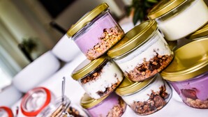 A display of layered desserts in jars with gold lids. - City Hotel (Brno)