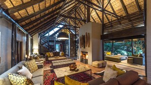 A spacious living area with high ceilings, a fireplace, and a view of the outdoors.