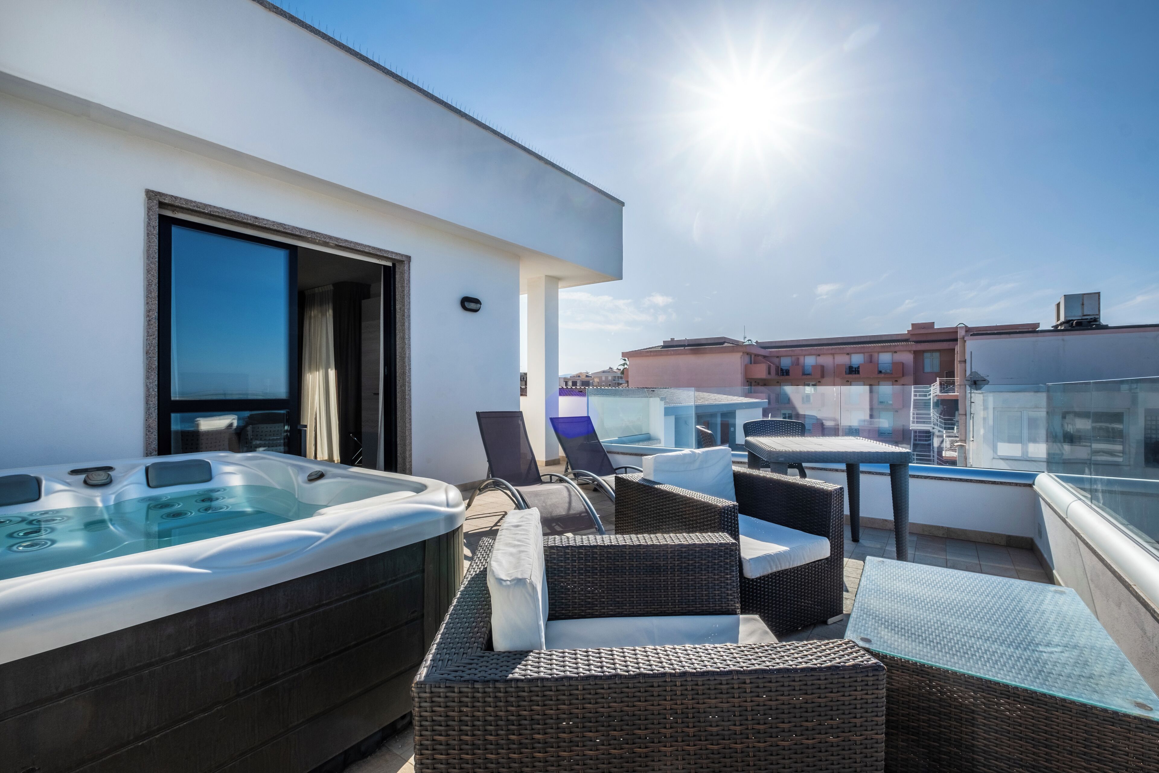 Una terrazza sul tetto con vasca idromassaggio, mobili in vimini e un tavolo in vetro.
