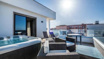 Una terrazza sul tetto con vasca idromassaggio, mobili in vimini e un tavolo in vetro.