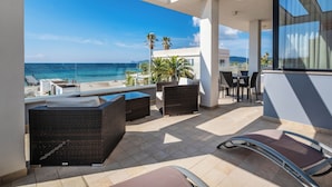 A balcony with wicker furniture, a glass table, and a view of the sea. - Residence Picalè (Alghero)