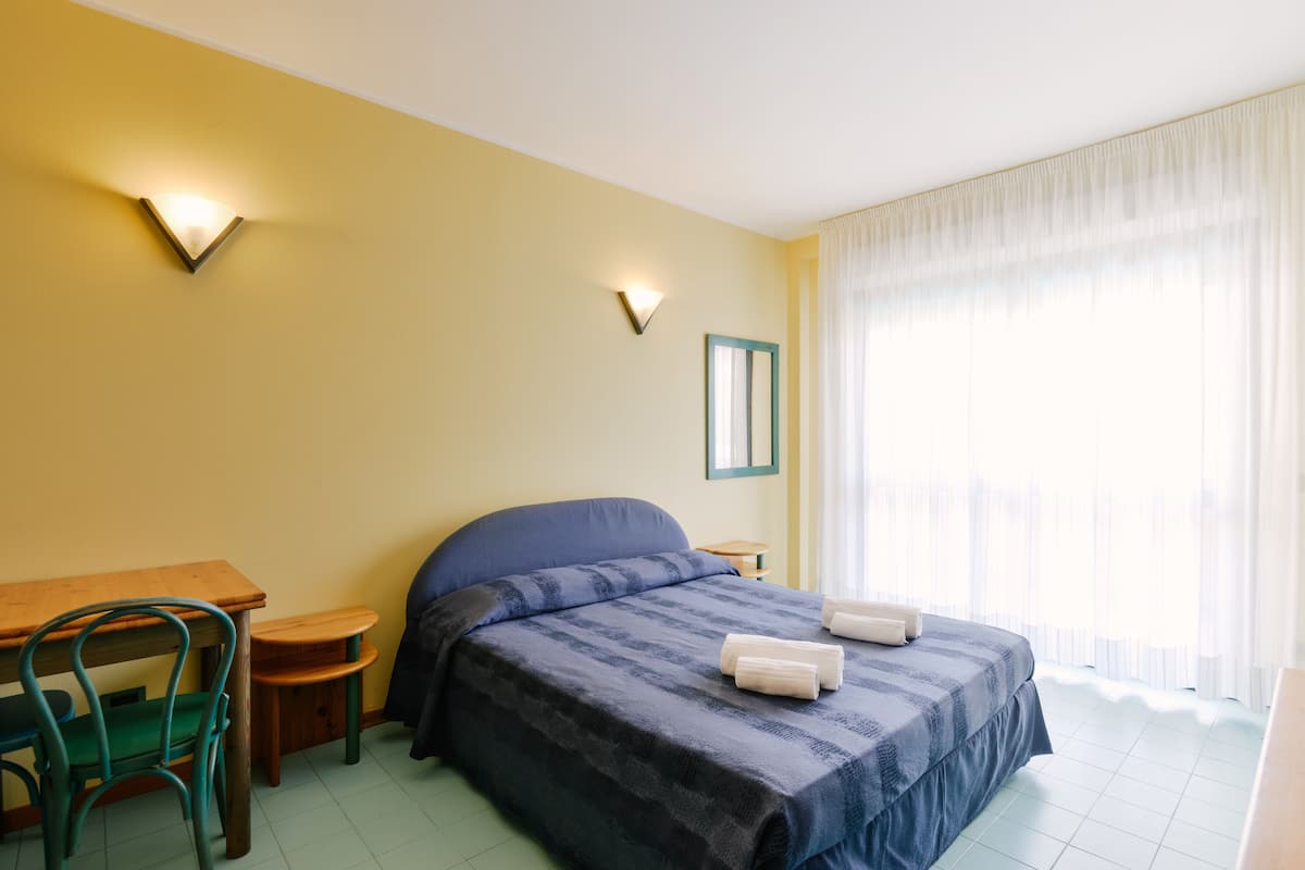 A hotel room with a bed, a desk, a chair, and a nightstand.