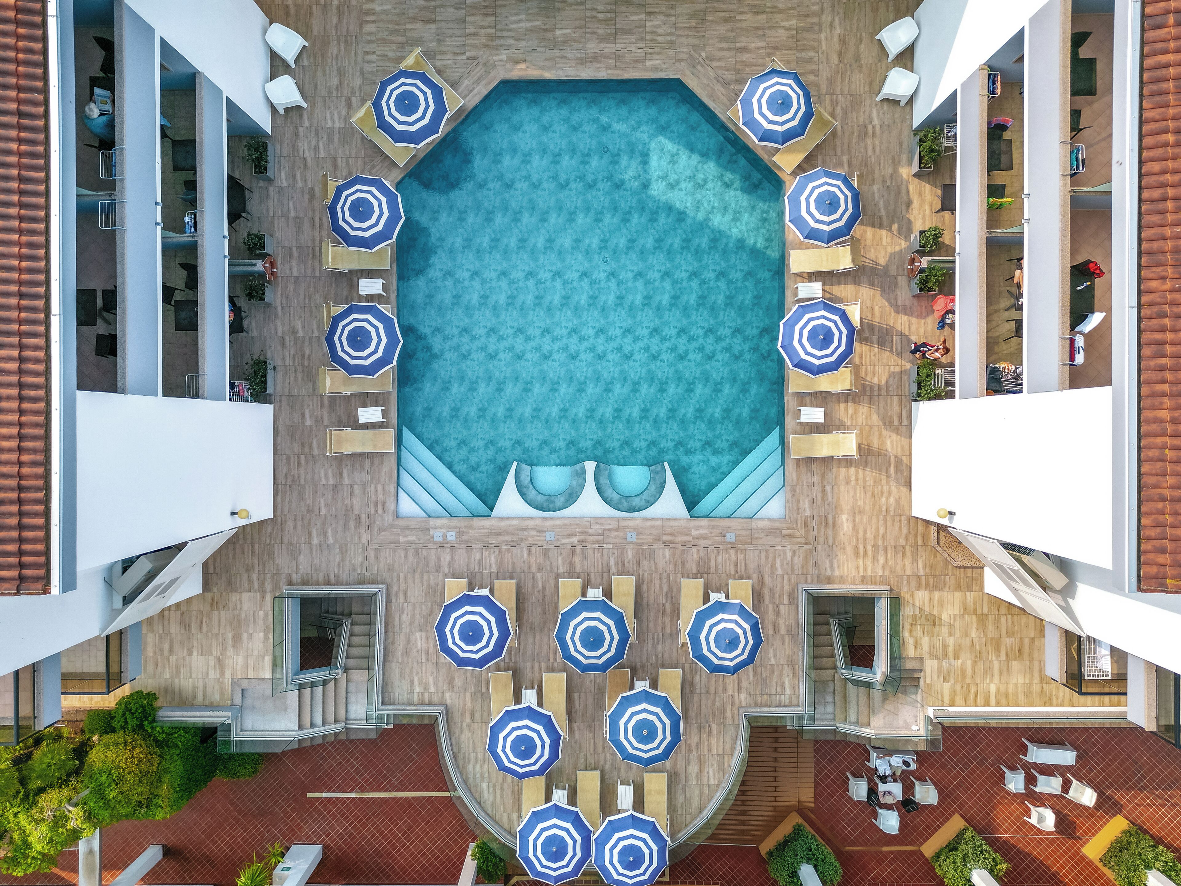 Un espace piscine sur le toit, doté de plusieurs coins salon et de parasols.