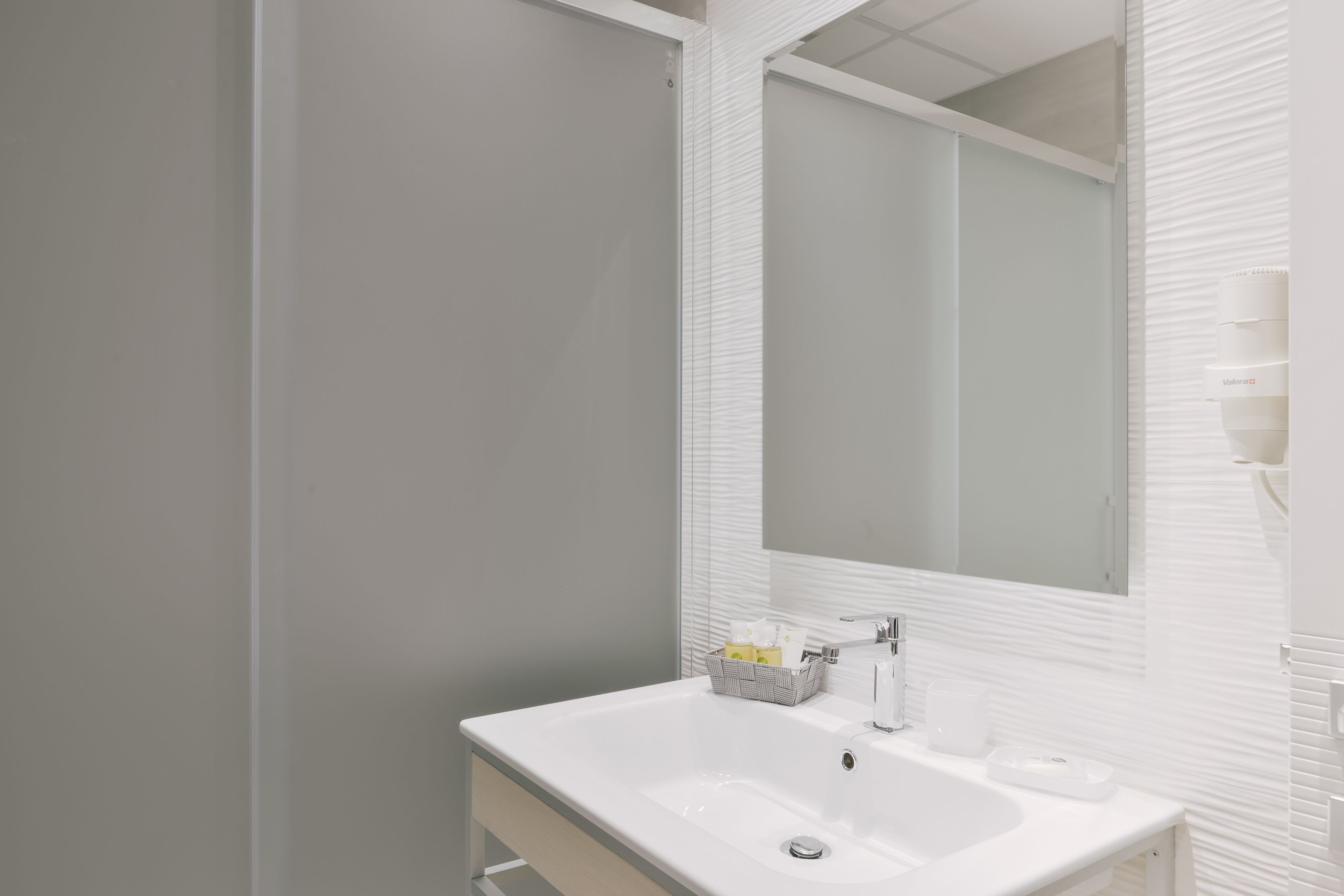 Een moderne badkamer met een witte wastafel, een spiegel en een handdoekhouder.