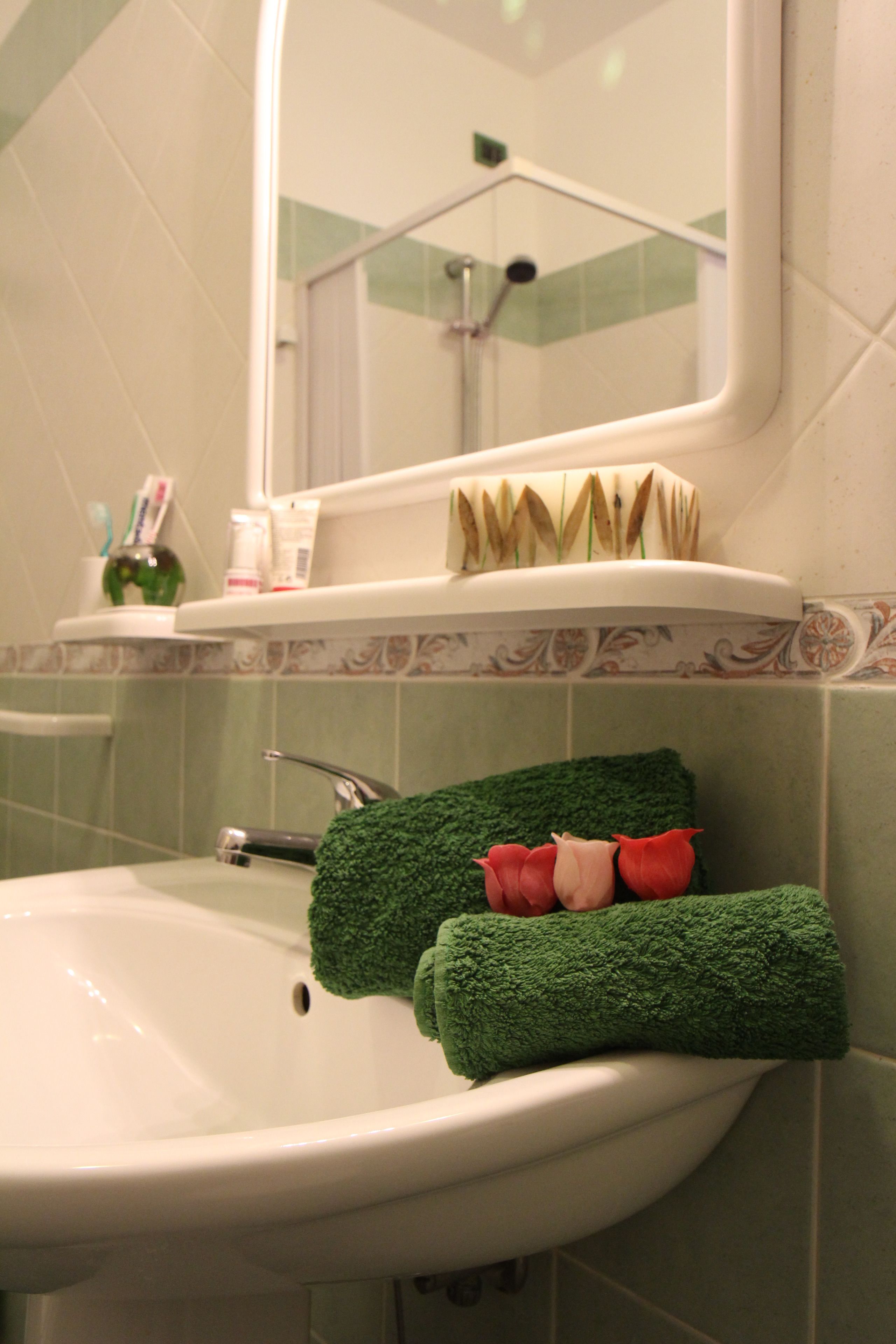A bathroom with a sink, mirror, and toiletries on the countertop.
