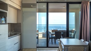 A modern kitchen with a view to a balcony, a dining area with chairs, and a large sliding glass door leading to the balcony. - Residence Picalè (Alghero)