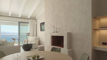 A modern living room with a fireplace, a dining table, and a view of the sea.