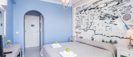 Un dormitorio con cama, escritorio, silla, candelabro y un mapa en la pared.