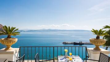 Terraza con mesa lista para el desayuno, con vista a un cuerpo de agua, un muelle y montañas distantes.