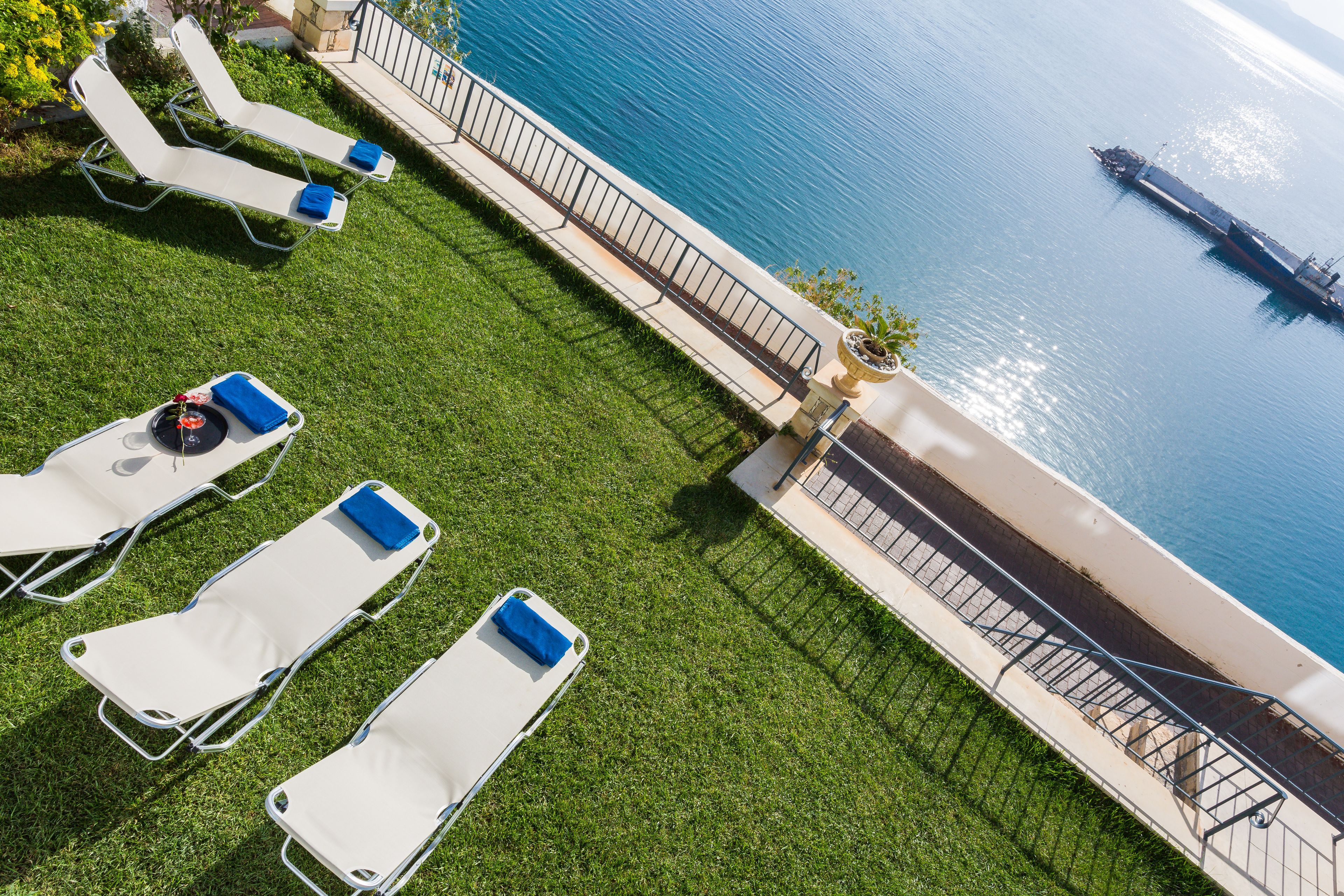 A rooftop terrace with lounge chairs and a view of the sea.