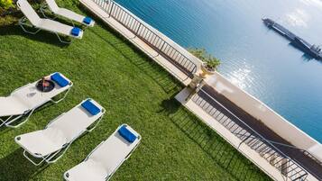A rooftop terrace with lounge chairs and a view of the sea.