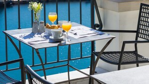 A table with breakfast items and drinks, overlooking a body of water and mountains. - Palazzo Greco (Agios Vasileios)