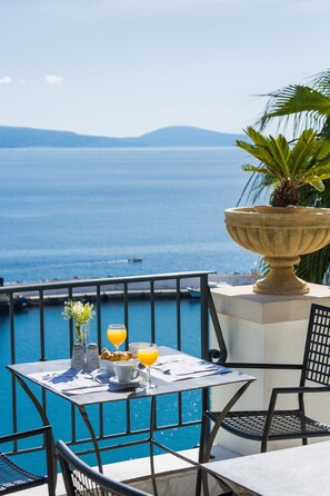 A table with breakfast items and drinks, overlooking a body of water and mountains. - Palazzo Greco (Agios Vasileios)