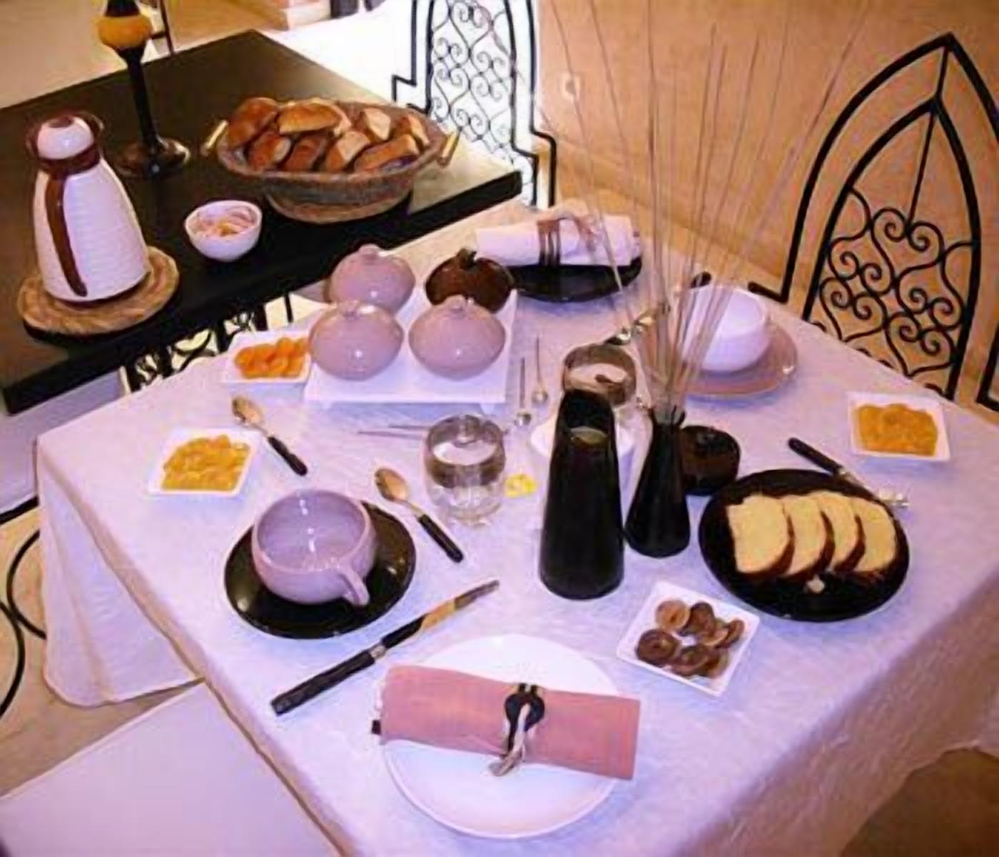 A table set with various dishes, including bread, a bowl of fruit, and a bottle.