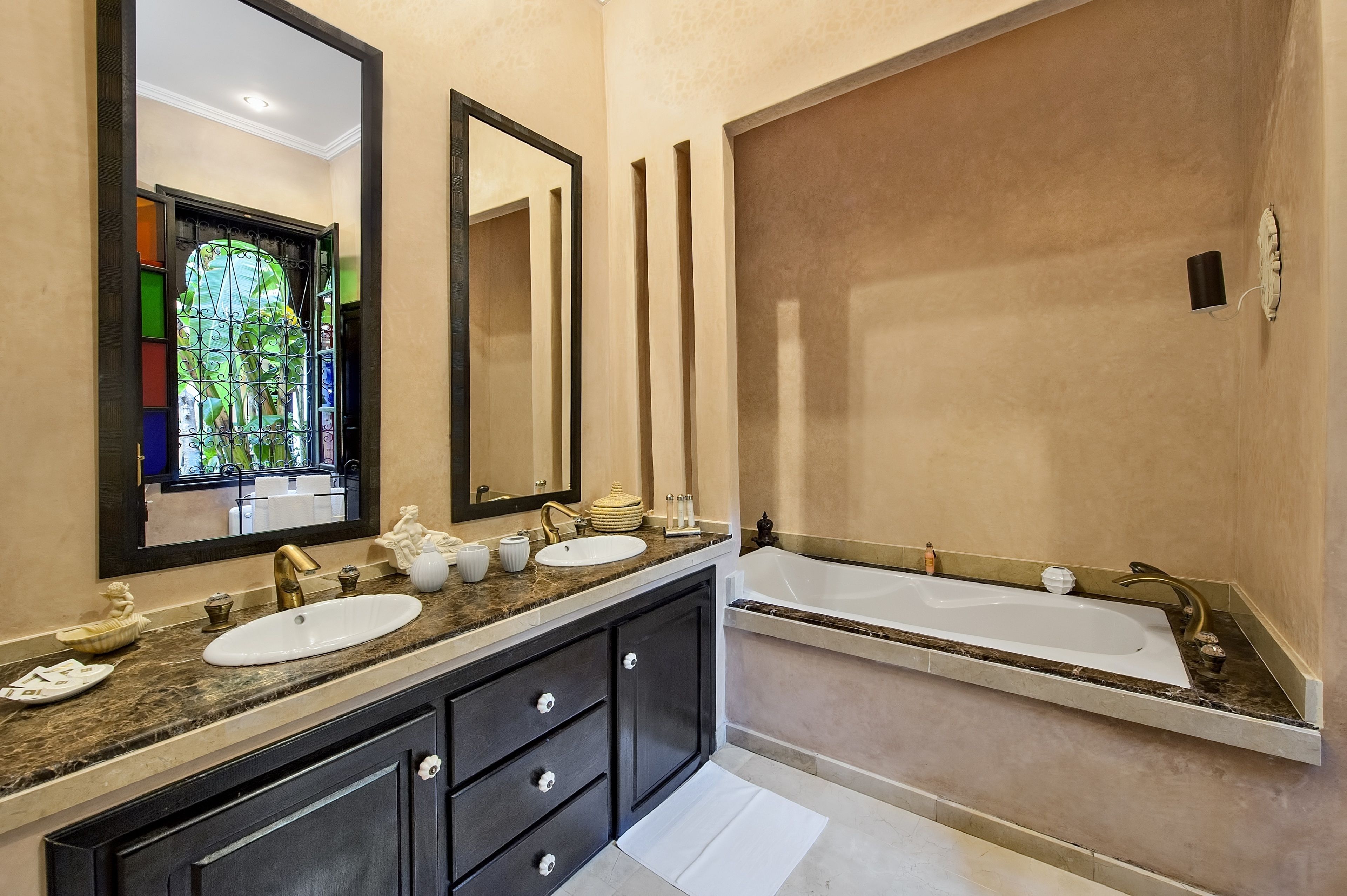 A modern bathroom with a large mirror, two sinks, a bathtub, and a vanity with drawers.