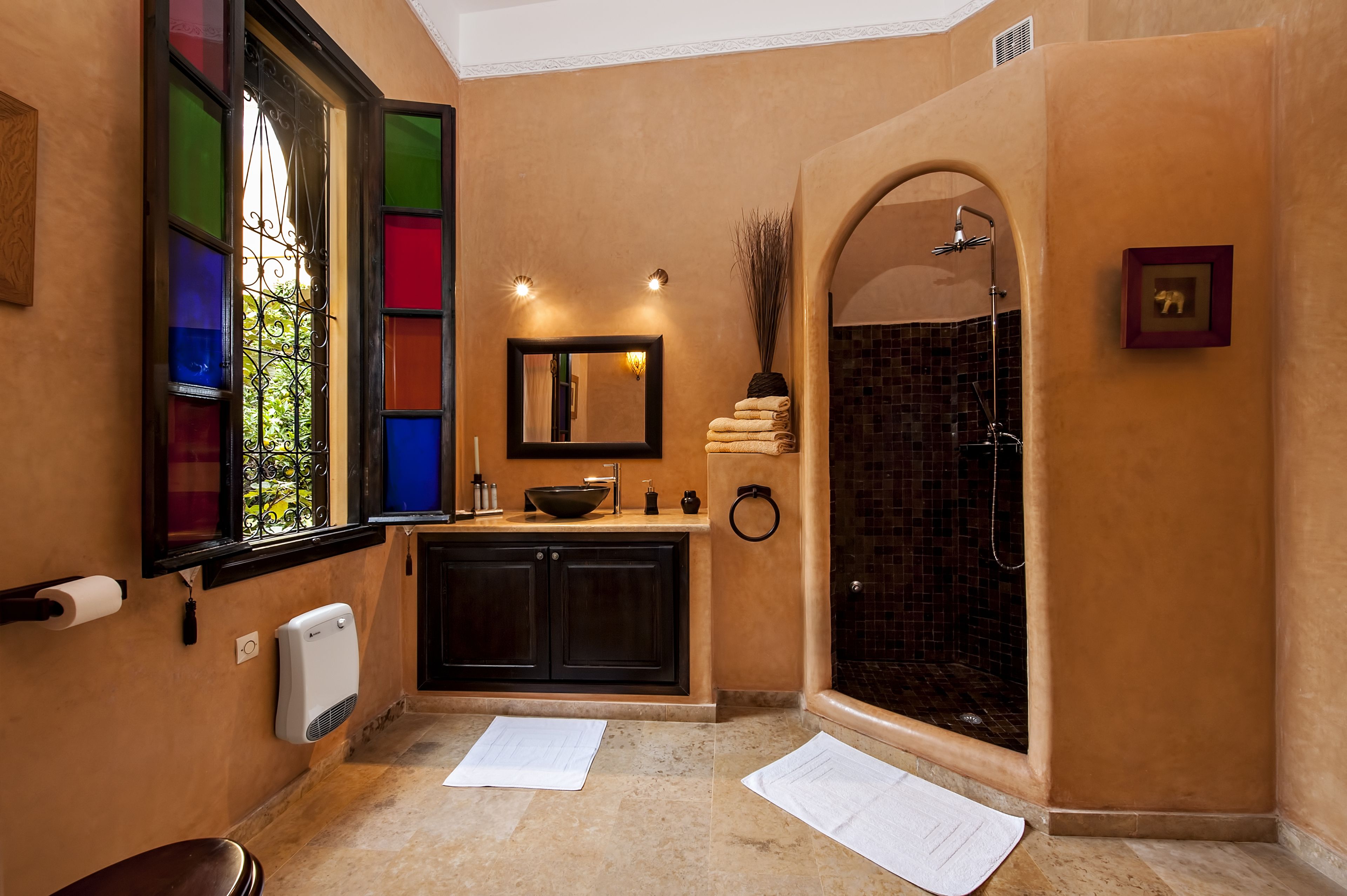 A bathroom with a large mirror, a sink with a bowl, a towel rack, and a shower with a tiled wall.