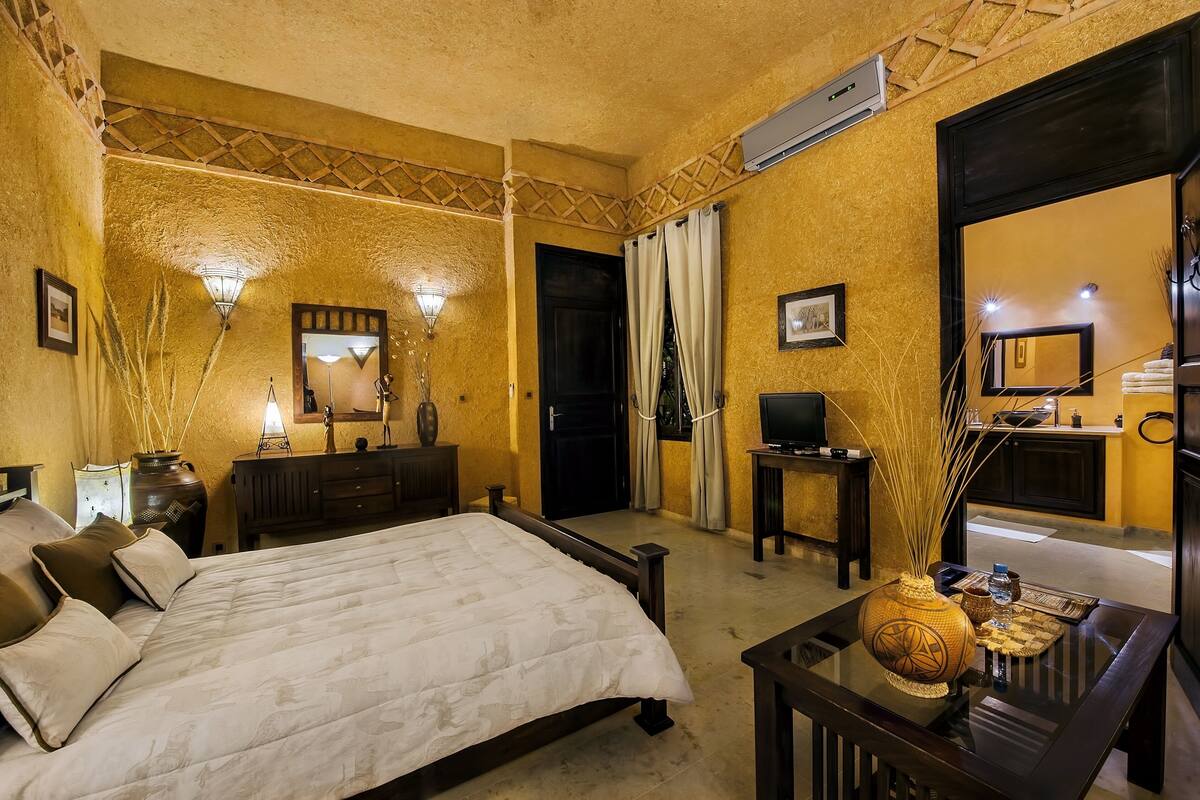 A hotel room with a bed, bedside table, lamp, and a mirror.