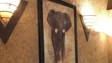 A framed elephant artwork on a textured wall with two wall-mounted lights.