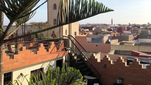 Eine Dachterrasse mit Blick auf eine Stadtlandschaft, darunter ein Turm und Wohnhäuser.