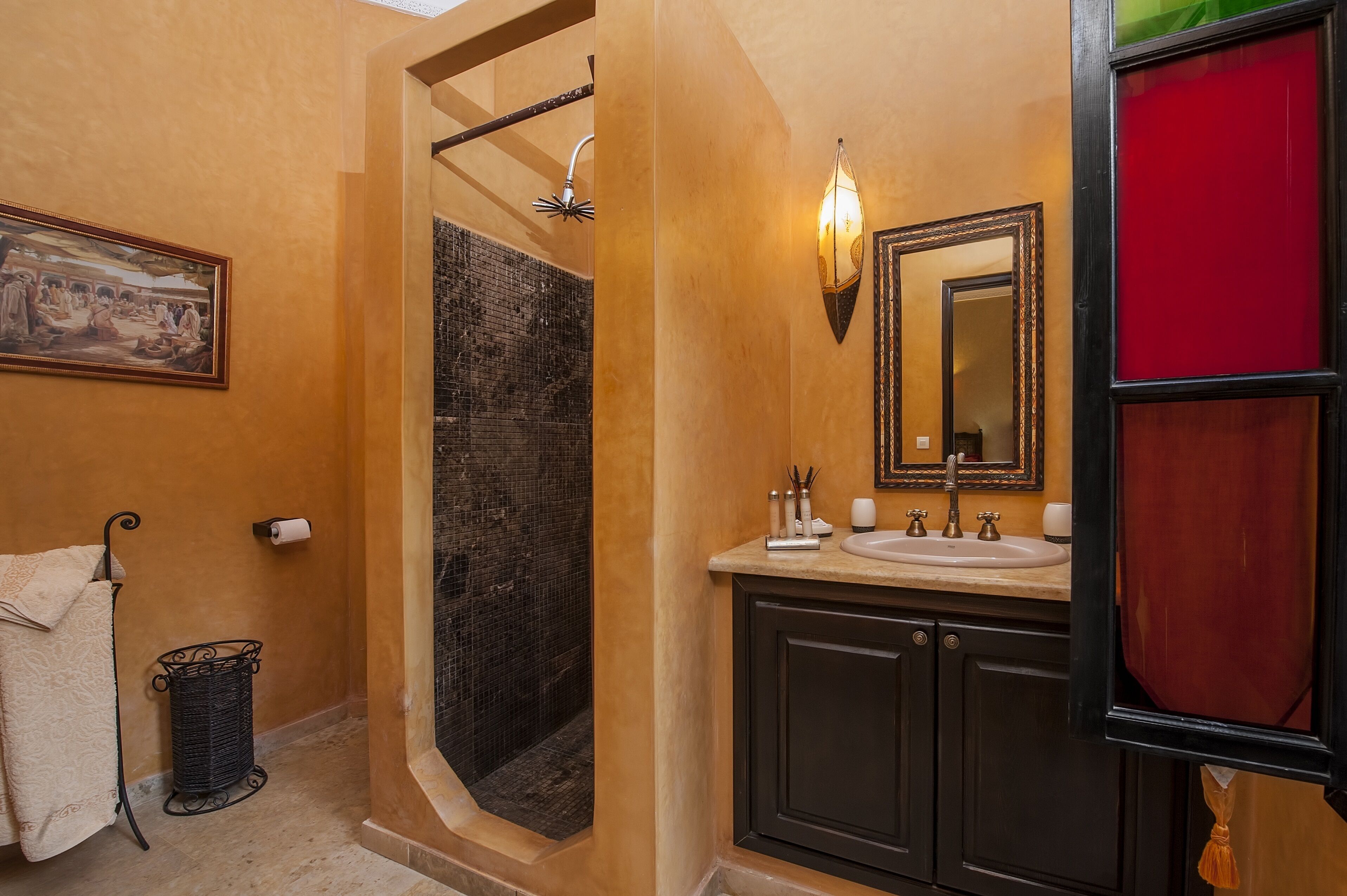 A bathroom with a shower, a sink, a mirror, and a towel rack.