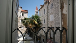 A narrow street with buildings, a palm tree, and a bell tower. - Villa Carrara (Trogir)