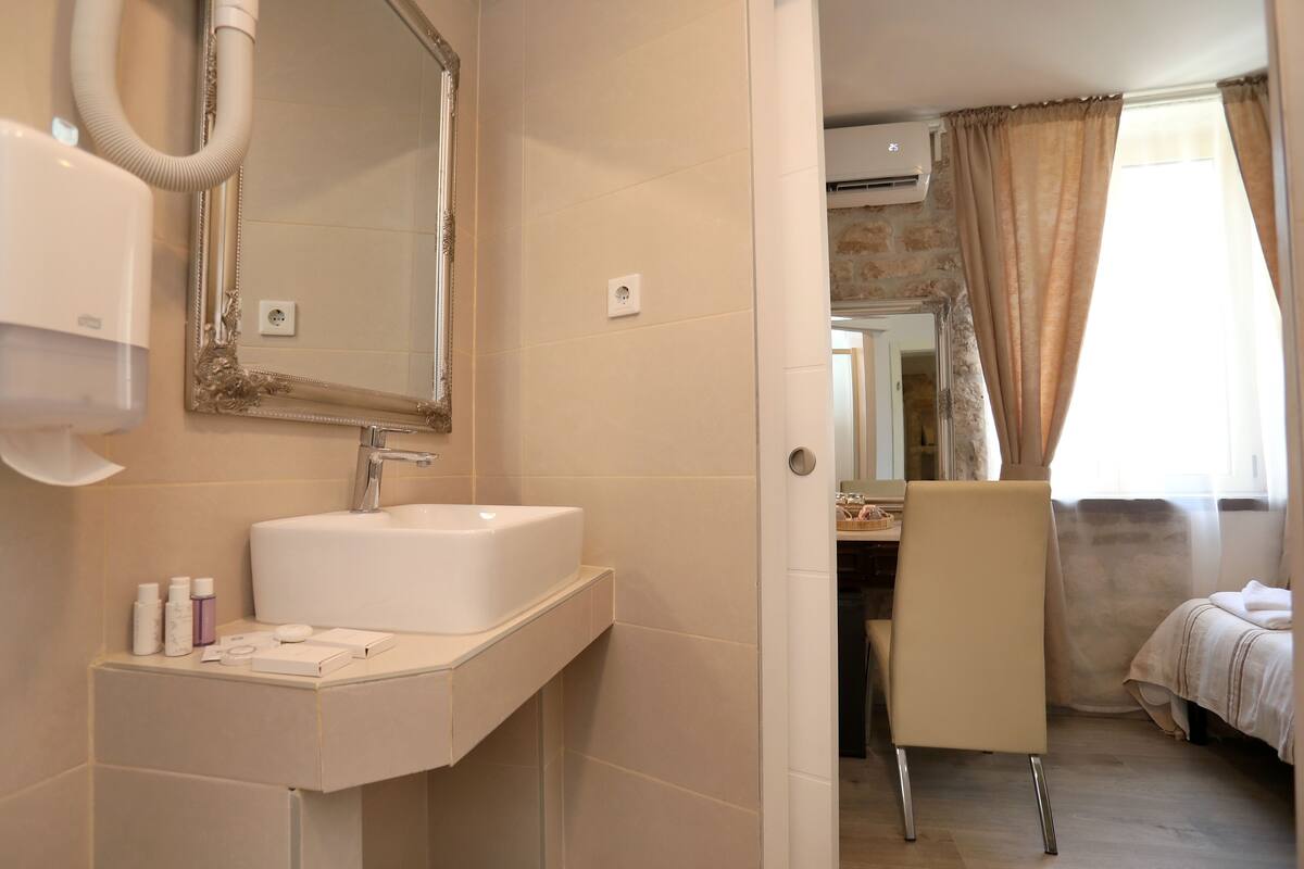 A bathroom with a sink, mirror, and toiletries.