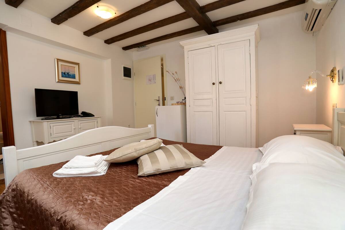 A bedroom with a bed, a television, a wardrobe, and a bedside table.