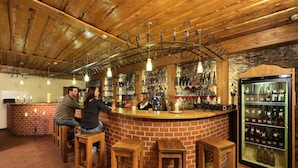 A bar area with wooden stools, a brick counter, and a wine refrigerator. - Hotel Záviš z Falkenštejna (Hluboka nad Vltavou)
