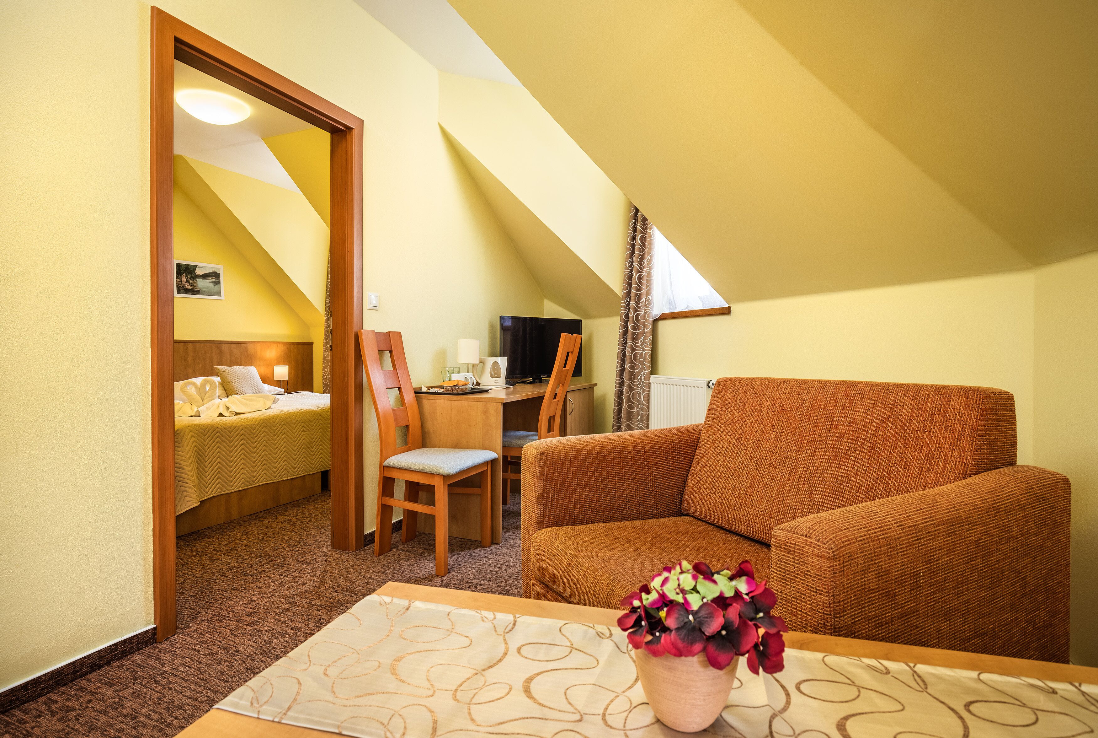 A cozy room with a bed, a sofa, a desk, and a chair.