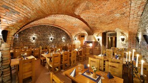 A restaurant with brick arches, wooden tables, and candles. - Hotel Záviš z Falkenštejna (Hluboka nad Vltavou)