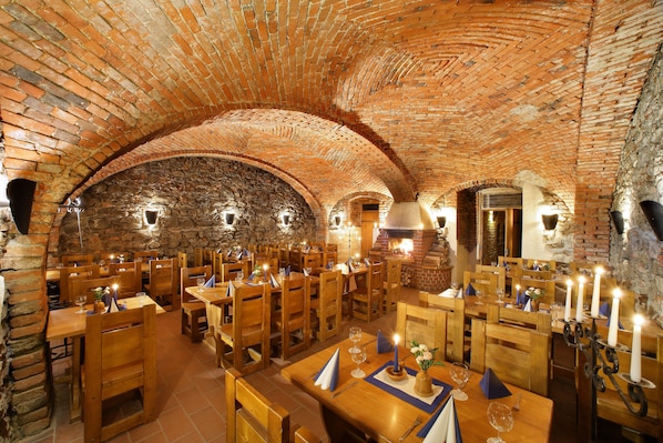 A restaurant with brick arches, wooden tables, and candles.