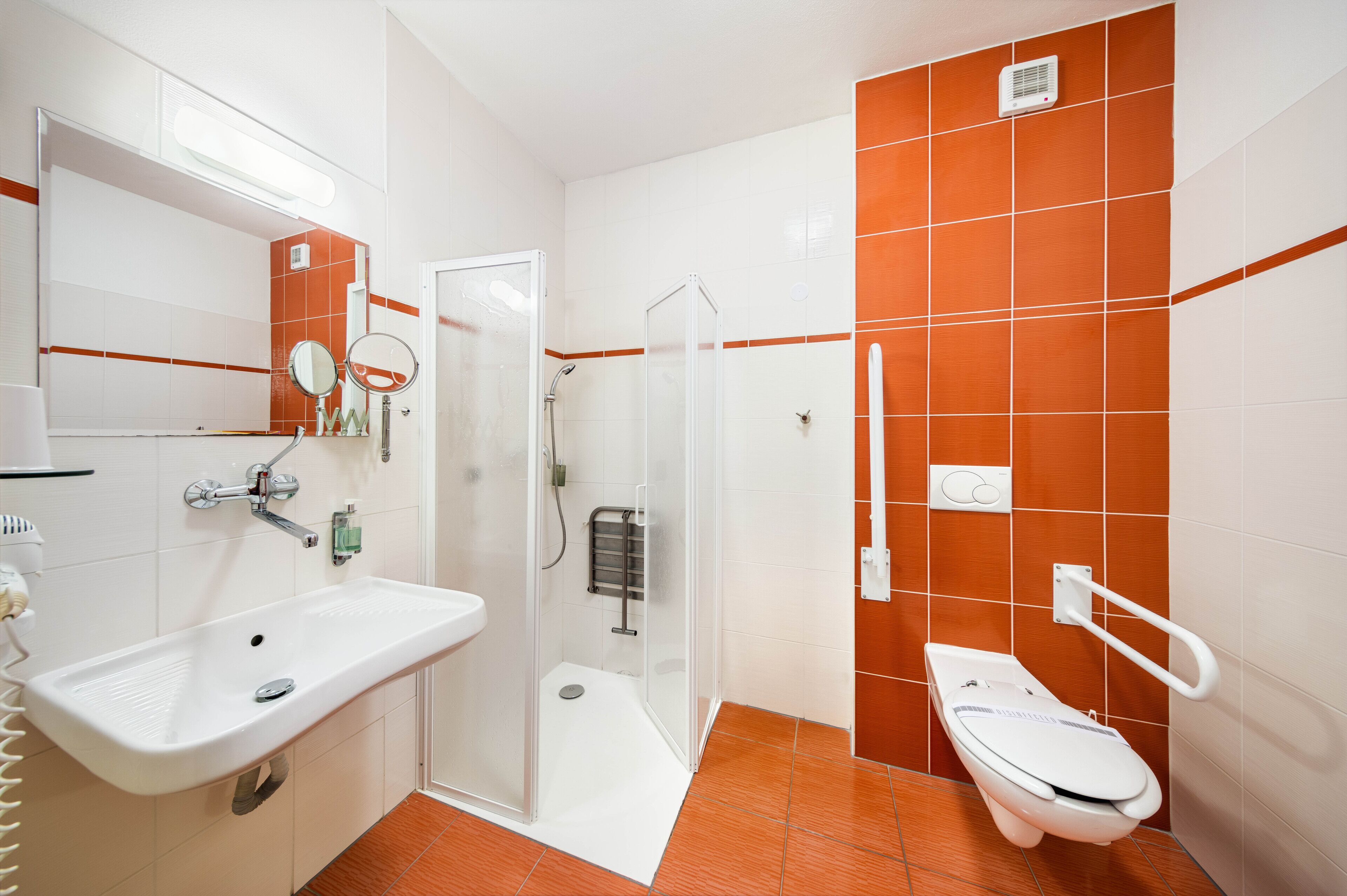 Une salle de bain équipée d’une douche, de toilettes, d’un lavabo et d’un miroir.