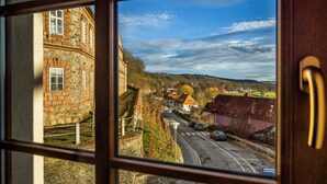 A view through a window of a street with buildings, a clear sky, and a distant hill. - Hotel Záviš z Falkenštejna (Hluboka nad Vltavou)