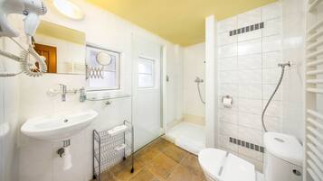 Un baño con lavamanos, espejo, secador de pelo, ducha e inodoro.