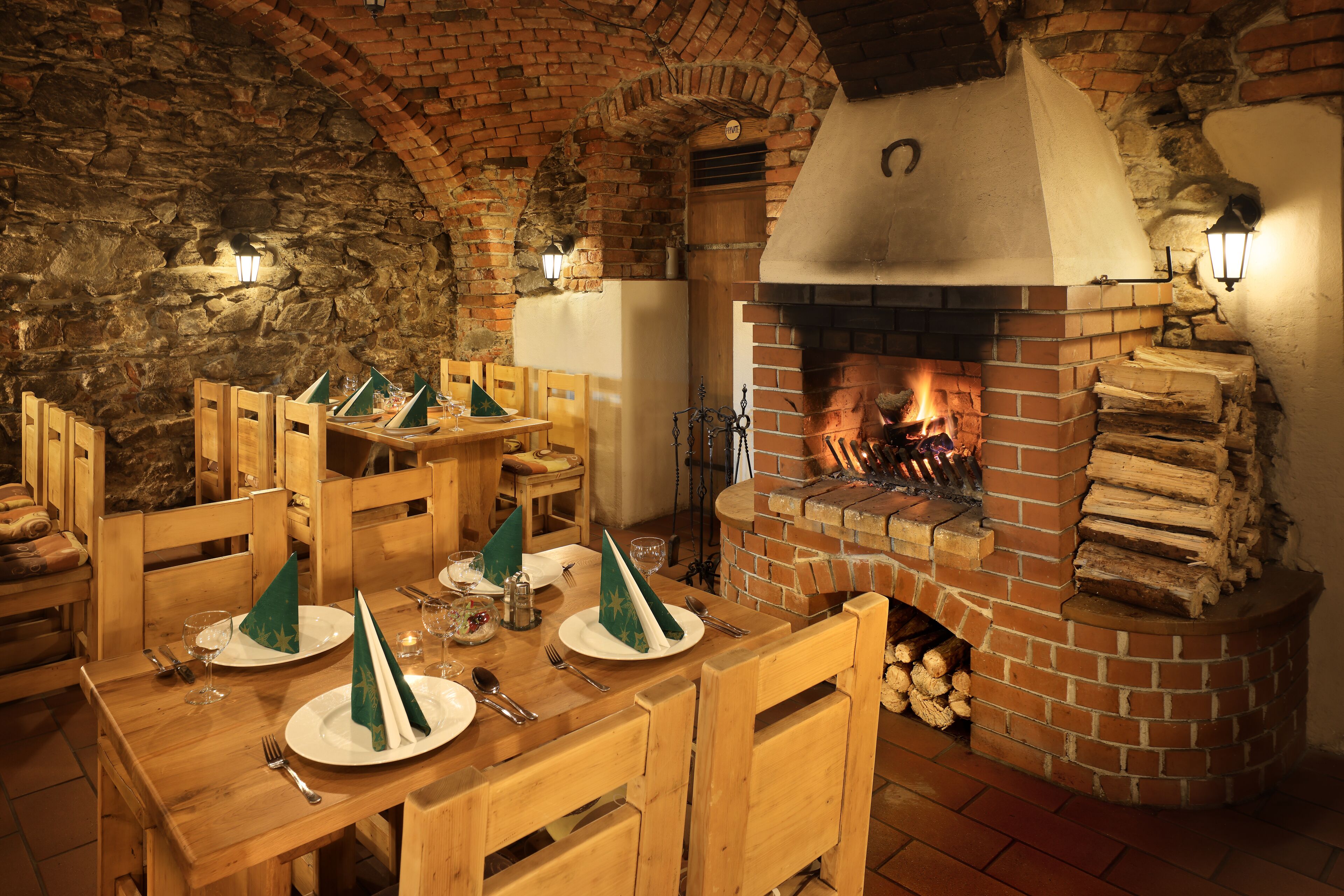Un comedor rústico con muebles de madera, chimenea de ladrillo y pared de piedra.