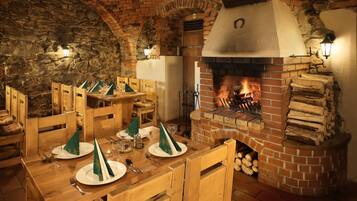 Un comedor rústico con muebles de madera, chimenea de ladrillo y pared de piedra.