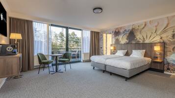Habitación de hotel con una cama grande, un escritorio con computadora, una silla y vistas al exterior.