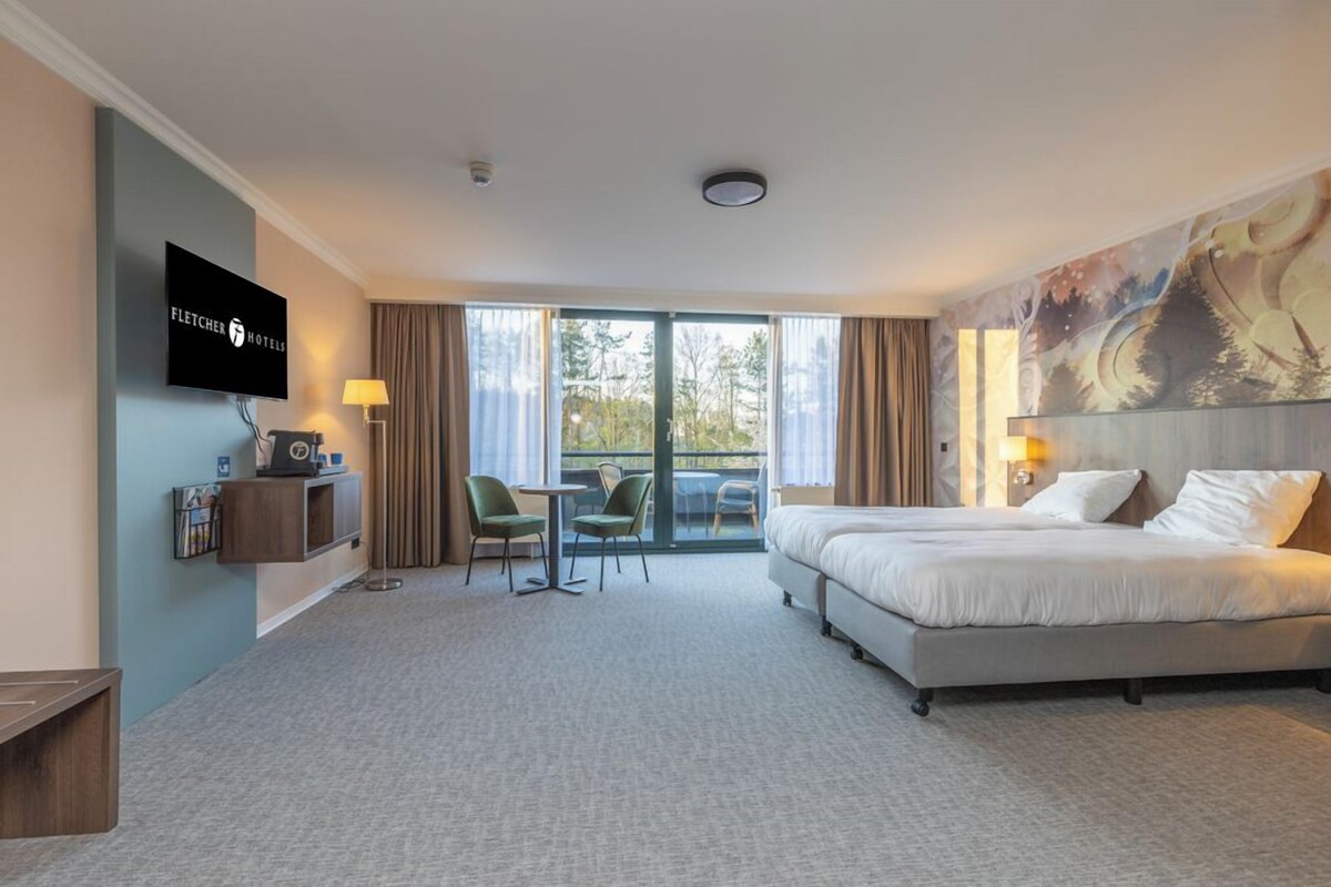 Een hotelkamer met een bed, een televisie, een bureau, een stoel en uitzicht op de omgeving.