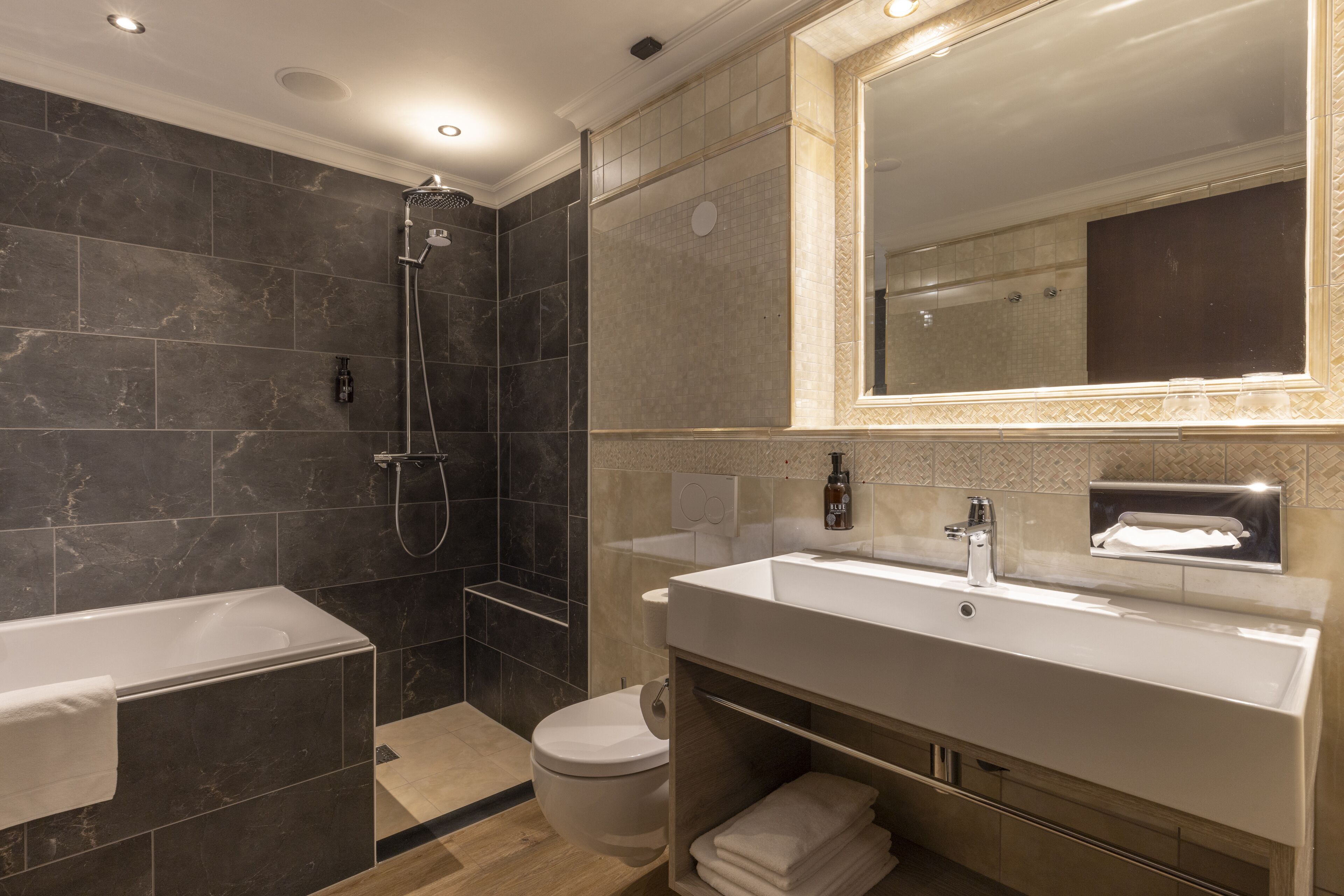 Un baño moderno con bañera, ducha, inodoro y tocador con espejo.