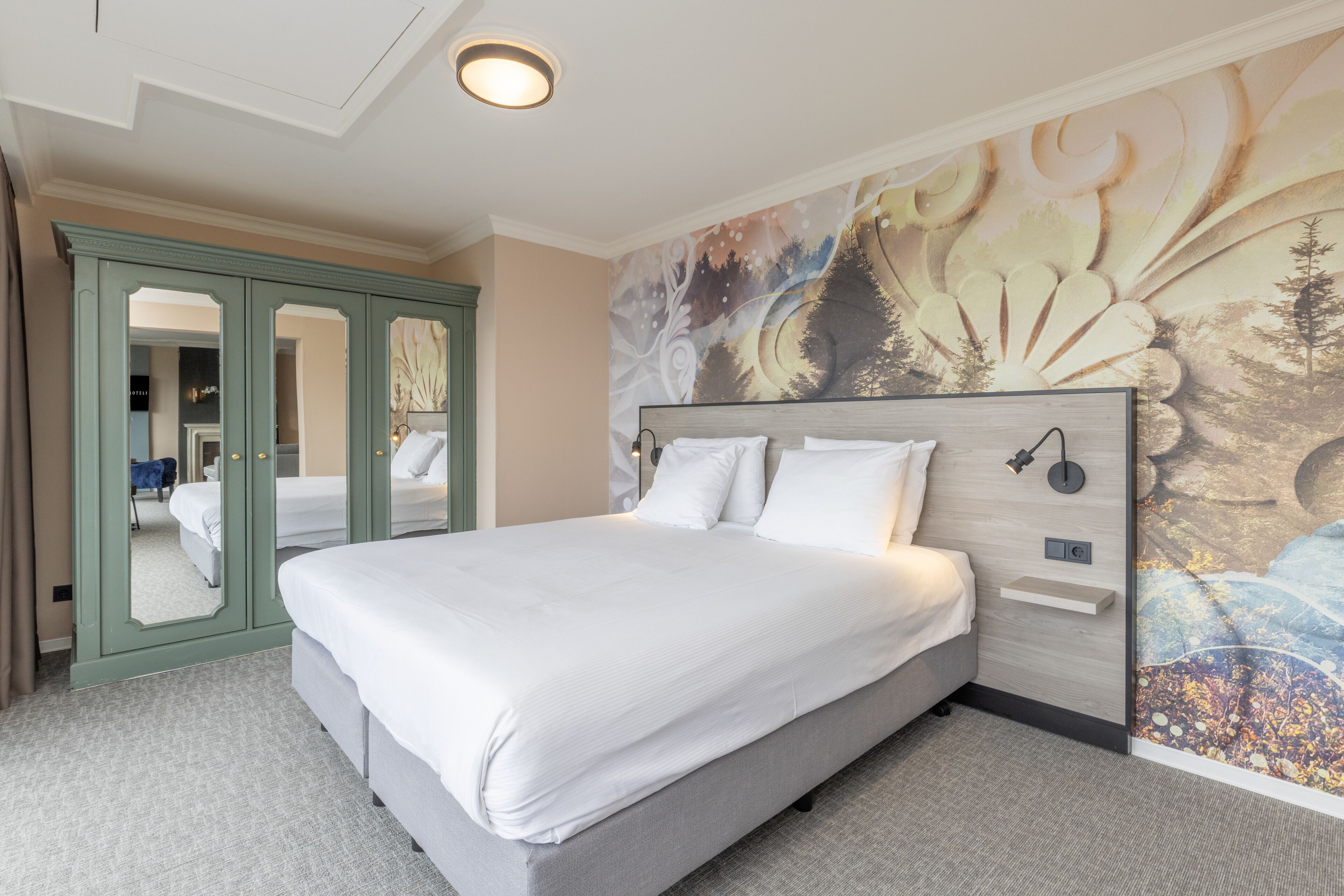 Una cama bien hecha en una habitación de hotel, con un espejo grande y un mural en la pared.