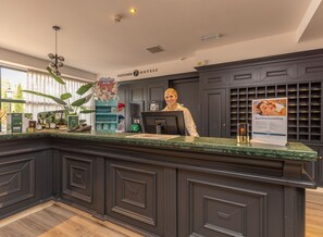 A hotel reception area with a dark wood reception desk, a computer, and a sign for 'Fletcher Kids'.