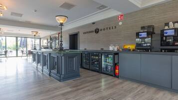 A hotel lobby with a reception desk, a coffee machine, and a fire extinguisher.
