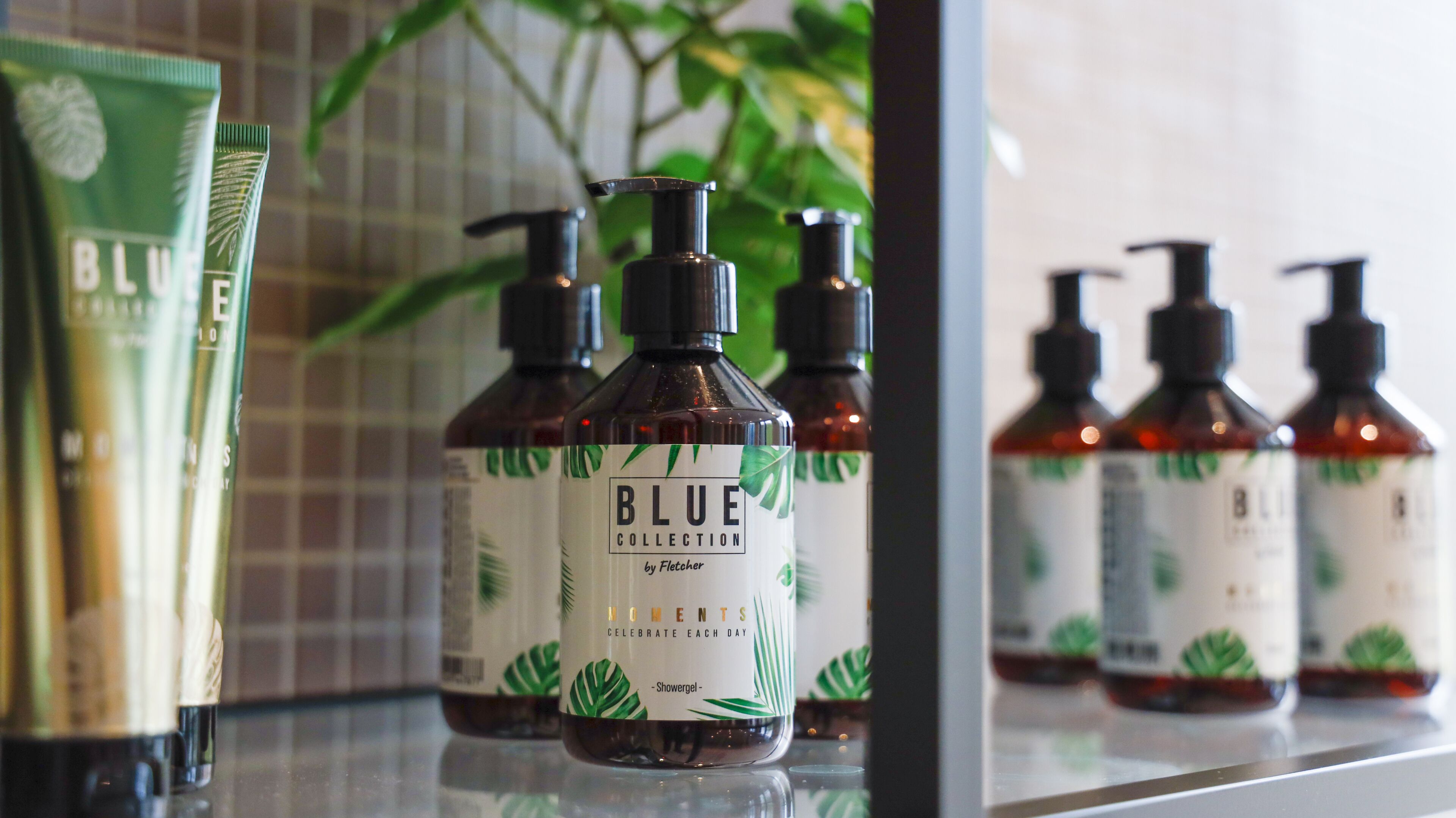 Un estante de baño con botellas de gel de ducha Blue Collection de Fletcher.
