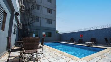 A swimming pool with lounge chairs and a barbed wire fence.