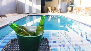 Ein Poolbereich mit einem grünen Eimer, der zwei Flaschen, Liegestühle und einen Glastisch enthält.