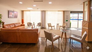 Eine Hotelhalle mit einer Ledersofa, einigen Stühlen, einem kleinen Tisch und einer Rezeption.